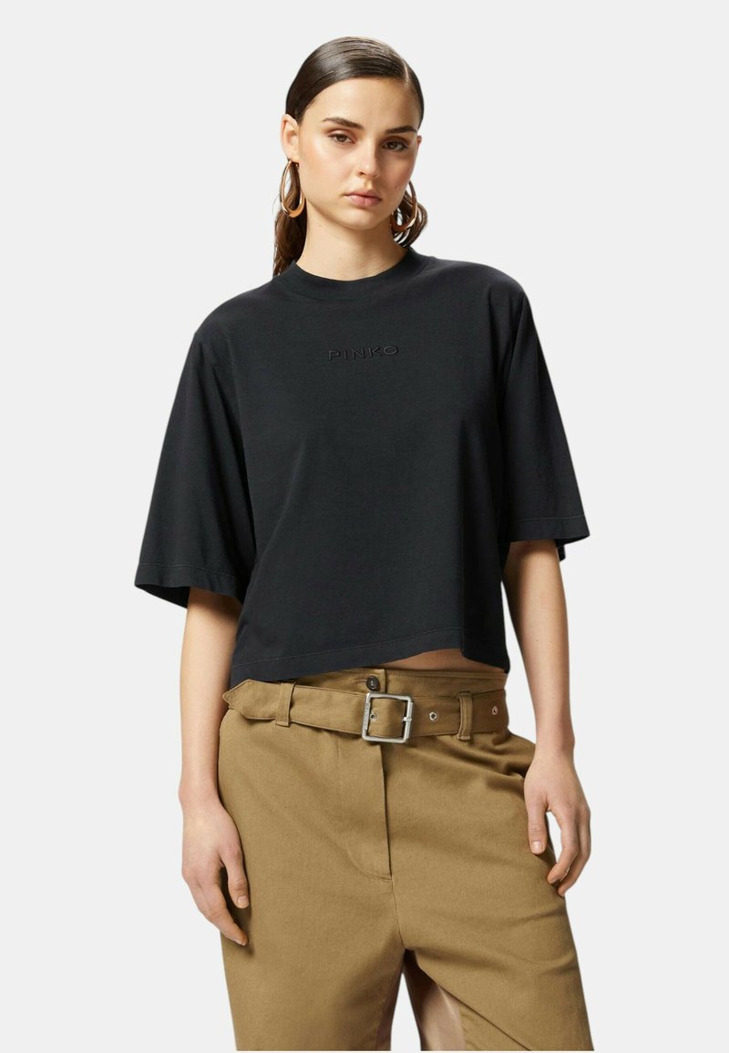 T-shirt nera corta con maniche corte e logo "PINKO" in rilievo. Abbinata a pantaloni khaki a vita alta con fibbia argentata.