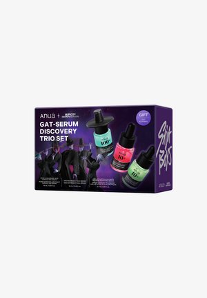 Boîte du coffret Anua Gat-Serum Discovery Trio avec trois flacons de sérum colorés et des silhouettes ombrées portant des chapeaux à larges bords sur un fond violet foncé.