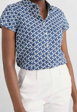 Kortærmet skjorte i blå og hvidt stof med fuglemønster, med en knaplukket krave og struktureret pasform, kombineret med hvide bukser.