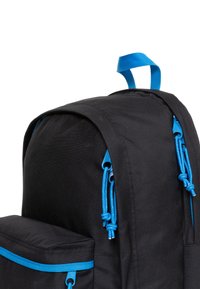 Sac à dos noir avec des accents de zip et de cordons bleu. Dispose d'une poche avant et d'une poignée de transport sur le dessus. Le matériau semble durable et texturé.
