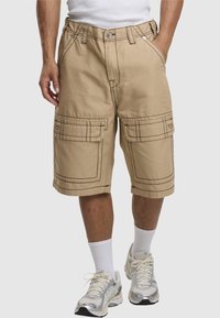 Beige Cargo-Shorts mit doppelten Fronttaschen und Kontrastnähten. Elastischer Taillenbund, gerade Passform, am Knie beschnitten.