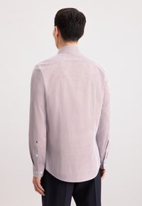 Camicia da uomo a maniche lunghe in rosa chiaro con piccolo motivo rosso, orlo dritto, colletto standard e polsini con bottoni in tessuto interno a contrasto.