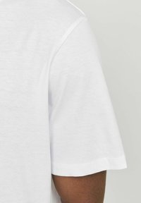 Kortærmet hvid bomulds t-shirt med rund halsudskæring og en glat tekstur, der har en klassisk pasform og pæne syninger langs sømmene.