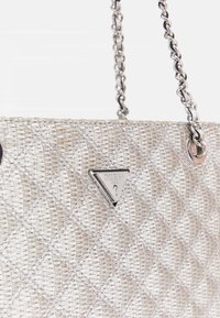 Zilveren, gewatteerde handtas van geweven materiaal met een kettinghangriem en een driehoekige logo-plaat aan de voorkant.