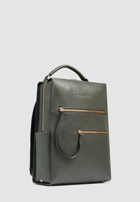 Sac à dos en cuir vert avec fermetures éclair dorées, deux poches avant, poignée latérale et finition texturée. Forme rectangulaire avec un design minimaliste.