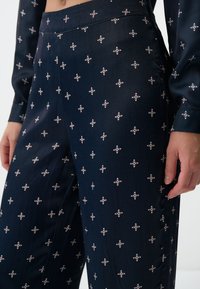 Navyblauwe geklede broek met een gladde stof, bloemachtige witte en rode accenten en een wijde pasvorm.