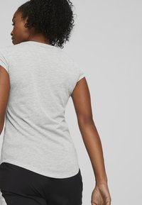 Tricou scurt gri cu mâneci scurte și guler rotund, având o textură netedă și o linie de tiv curbată. Vederea din spate arată un design ajustat.