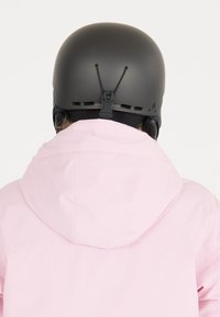 Pink waterproof jacket with a hood, paired with a matte black helmet. Features include adjustable straps and vent holes for breathability.