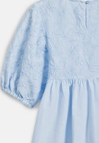 Světle modré šaty s vyšívaným květinovým vzorem, balónovými rukávy, zapínáním na knoflík na zadní straně a nařaseným pasem s volánovou sukní.