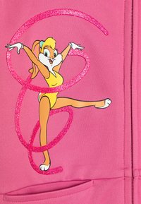 Rožinė tekstilė su animaciniu personažu geltonu kostiumu, apsuptu blizgančių rožinių spiralių, demonstruojančiu žaismingą pozą ir baltomis detalėmis.