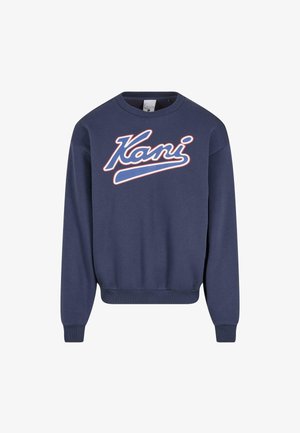 Tamsiai mėlynas džemperis su baltu ir raudonu švelniu užrašu "Kani" priekyje. Su gumuotais rankogaliais ir apačia, pagamintas iš švelnios medžiagos.