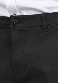 Schwarze Hose mit Knopfverschluss, glatter Textur und strukturiertem Bund, mit sichtbaren Nahtdetails und einem klaren, modernen Schnitt.
