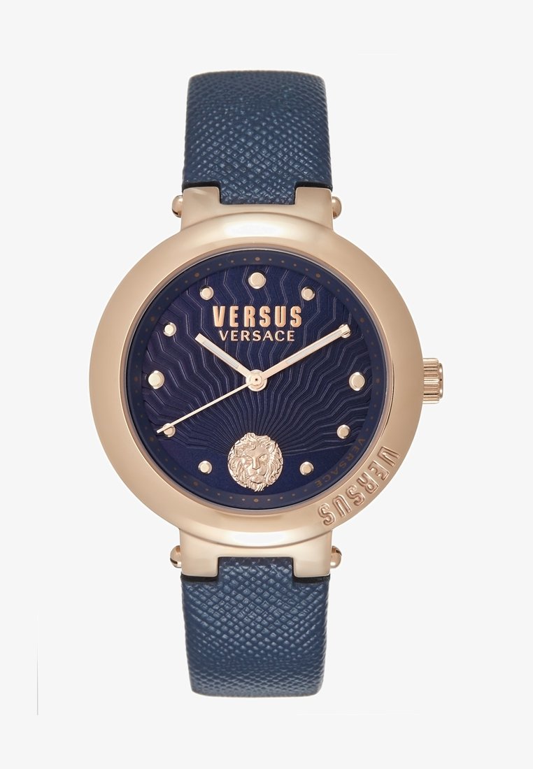 Montre Versus Versace ronde en ton or avec cadran bleu texturé, index dorés, emblème de lion à 6 heures, et bracelet en cuir bleu texturé.