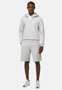 Lichtgrijze hoodie met een halve rits, bijpassende shorts en lichtgrijze sneakers. Glad materiaal, minimalistisch ontwerp en een ontspannen pasvorm.