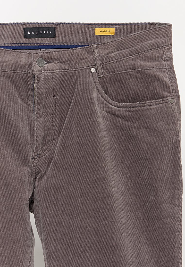 Pantalons en velours côtelé marron avec bouton frontal, fermeture éclair et deux poches avant, portant les étiquettes "bugatti" et "Modern" à l'intérieur de la taille.