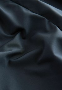 Donker marineblauw satijnen stof met een gladde textuur, die zachte plooien en een subtiele glans vertoont. Geen patronen of zichtbare hardware.