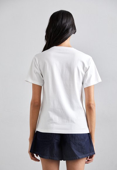 Weißes Baumwoll-T-Shirt mit kurzen Ärmeln, Rundhalsausschnitt und glatter Textur, kombiniert mit dunklen Jeansshorts. Keine sichtbaren Grafiken oder Muster.