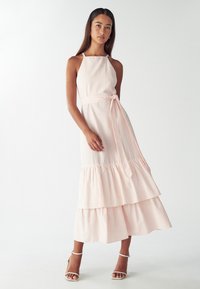 Vestido maxi a rayas en rosa claro y blanco, con corpiño ajustado, cuello halter y dobladillo con volantes en capas. Incluye un cinturón a juego.