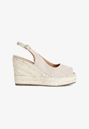 Sandalias de cuña beige con parte superior de tela texturizada, punta abierta y diseño de tira trasera. Suela de yute estilo espadrille con detalles trenzados.