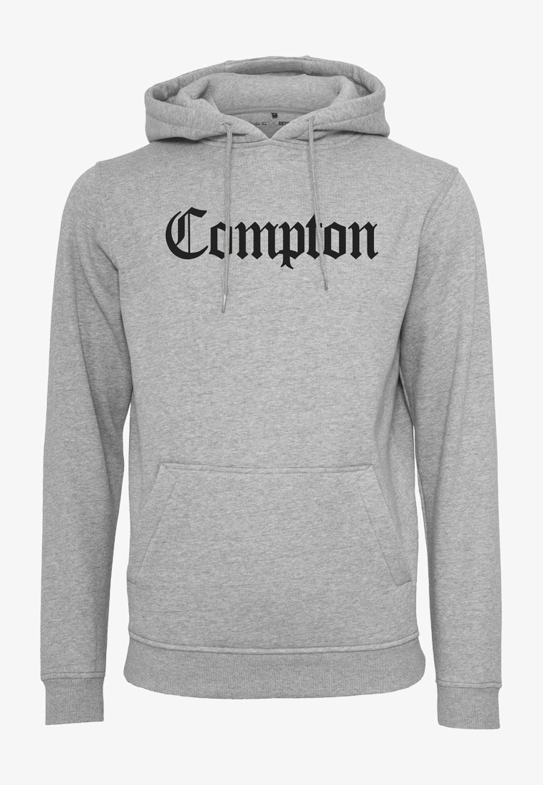 Šedá bavlněná mikina s kapucí, která má přední kapsu a černý nápis "Compton" v tučném, dekorativním písmu.