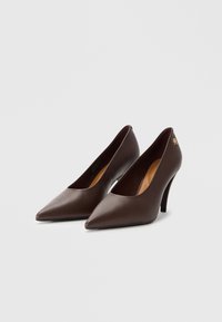 Brune lær høye hæler med spiss tå, lav utskjæring og et elegant design. Har en gulllogo aksent på hælen.