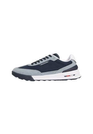 Zapatillas con un esquema de colores en gris y azul marino, materiales de gamuza y malla, diseño de cordones y una suela blanca gruesa con detalles de acento.