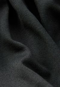 Zwart materiaal met een gladde textuur, met een subtiele glans en een lichte rek. Het materiaal lijkt zacht en valt in zachte golven.