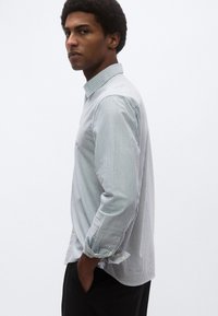 Ριγέ πουκάμισο με κουμπιά σε ανοιχτό μπλε και λευκό, με κλασικό γιακά, μακριά μανίκια και μανσέτες με κίτρινα κουμπιά.