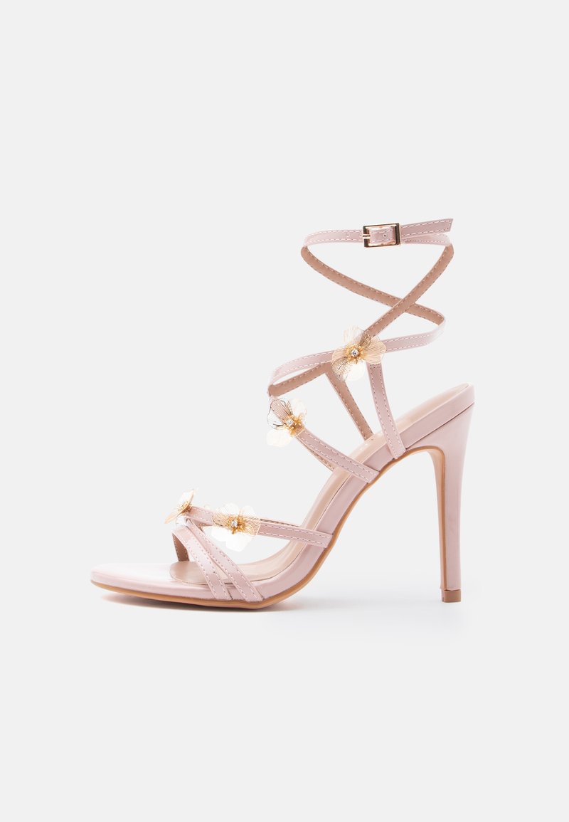 Sandales à talons hauts rose blush avec plusieurs fines lanières, accents floraux sur la partie supérieure et une finition brillante sur le bout et le talon.