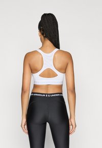 Λευκό αθλητικό σουτιέν με σχεδιασμό racerback, με λεπτομέρεια κοψίματος, σε συνδυασμό με μαύρο εφαρμοστό κολάν με λογότυπο στη μέση.