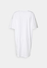 Robe t-shirt oversize blanche à manches courtes, vue de dos sur un fond gris clair.