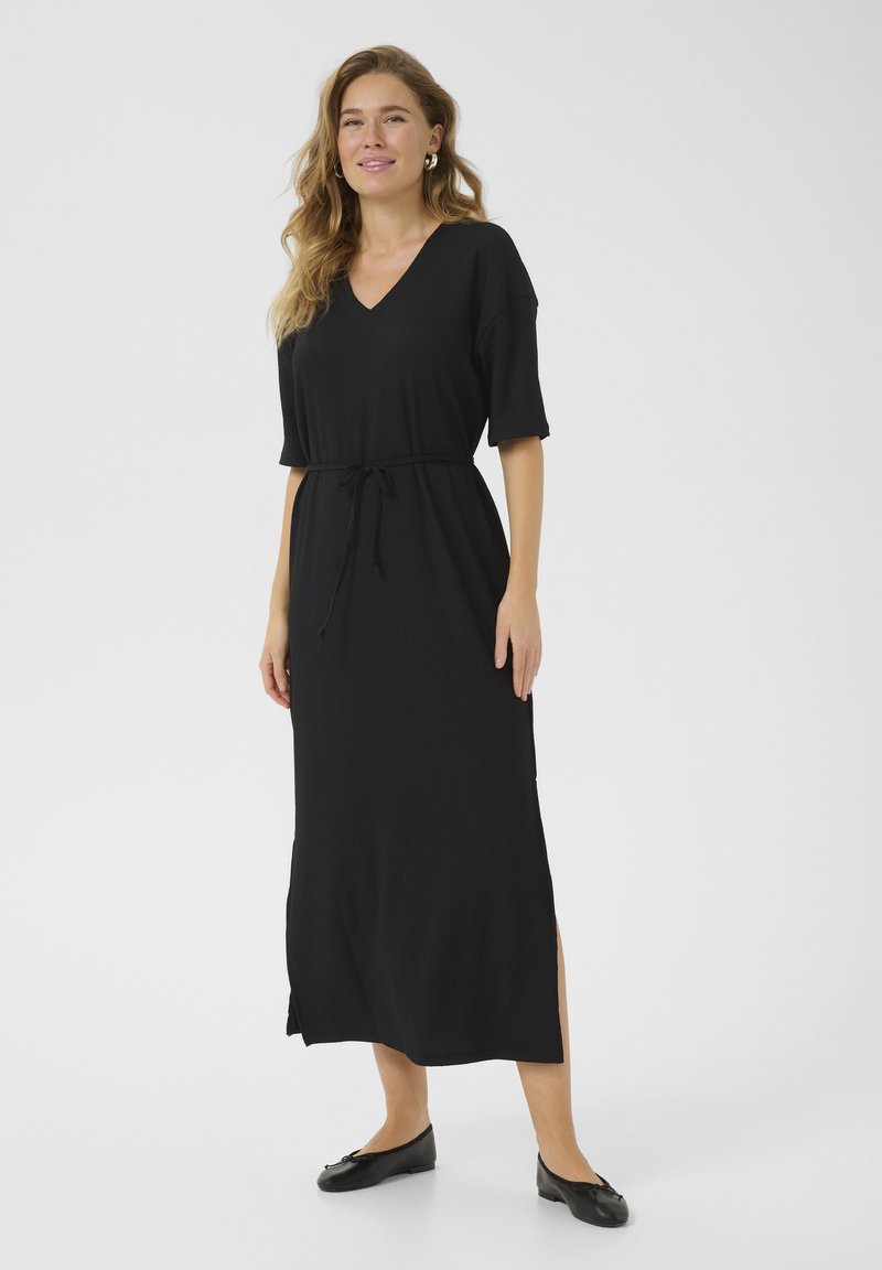 Robe noire, longueur genoux, avec un col en V, manches courtes, taille à cordon de serrage et fentes latérales. Texture lisse, fabriquée à partir d'un tissu léger.