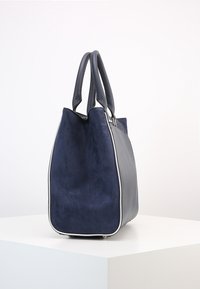 Námořnická kabelka z faux suede s hladkými koženými akcenty. Zúžený design, dvojité horní uši a kontrastní bílé lemování kolem okrajů.