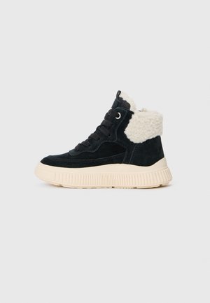 Schwarzer Wildleder-High-Top-Sneaker mit cremefarbener Gummisohle und weißem Fleece-Kragen, von der Seite vor neutralem Hintergrund gesehen.