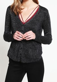 Svart, glittrig långärmad kofta med V-ringning och knäppning, med kontrasterande burgundy band under.