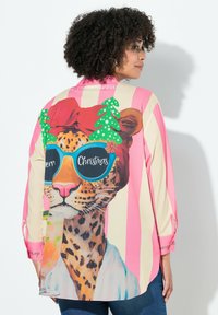 Koszula na guziki z kolorową grafiką lamparta, z zielonymi akcentami w postaci choinek świątecznych i różowymi pionowymi paskami. Długie rękawy z podwiniętymi mankietami.