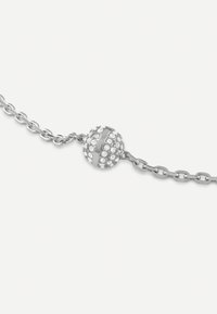 Bracelet en argent présentant un médaillon sphérique orné de petites cristaux transparents, relié par une chaîne délicate.