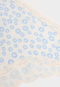 Sous-vêtements en coton avec un fond crème et un petit motif floral bleu. Présentent une bordure en dentelle sur les bords et une texture subtile.