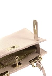 Lichtroze, gestructureerde lederen tas met een gouden sluiting, gekenmerkt door een interieur van contrasterend gouden leer en een veilige riembevestiging.