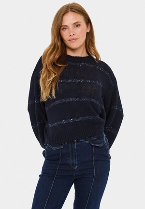 Marine gestreepte gebreide trui met een losse pasvorm, textuurstof en ronde halslijn, gecombineerd met donkere high-waisted jeans.
