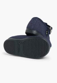 Zapatos de tela de color azul marino con parte superior texturizada, punta redonda y acento de hebilla. Suela de goma negra duradera con patrón antideslizante.