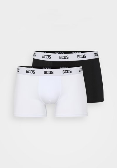 Due paia di boxer GCDS; uno nero e uno bianco. Entrambi presentano una cintura elastica con il logo GCDS ben visibile stampato in nero.