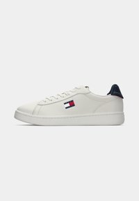White faux leather sneakers with navy blue heel accent, lace-up design, and small red, white, and blue logo on the side. Smooth texture.