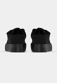 Sorte joggesko med teksturert stoffoverdel, rundet tå, elastisk krage og tykk gummisåle. Minimalistisk design uten merkbare pynt.