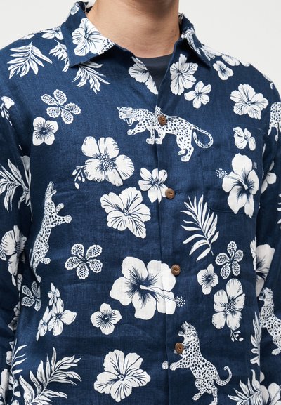 Πουκάμισο σε ναυτικό μπλε χρώμα με λευκά λουλουδένια και λεοπάρ μοτίβα, με ξύλινα κουμπιά και τσέπη στο στήθος.