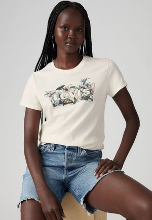 Cremfarbendes T-Shirt mit floralem Levi's-Logo auf der Vorderseite, kombiniert mit hellblauen Denim-Shorts mit fransigen Kanten.