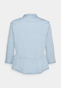 Ljusblå denimjacka med peplumslut, långa ärmar och klassisk krage. Tyget ser mjukt ut med en något urtvättad look.