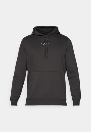 Hoodie noir avec une poche kangourou, cordons au cou et un petit logo blanc sur la poitrine. Fabriqué à partir d'un tissu lisse et texturé.