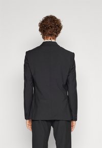 Schwarze Anzugjacke mit tailliertem Schnitt, mit Reverskragen, einem Schlitz hinten und gefütterten Manschetten. Glatte Stoffoberfläche.