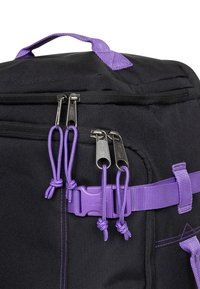 Zaino nero con cursori della cerniera, cinghie e fibbia viola. Presenta più scomparti e dettagli di cuciture per maggiore durata.
